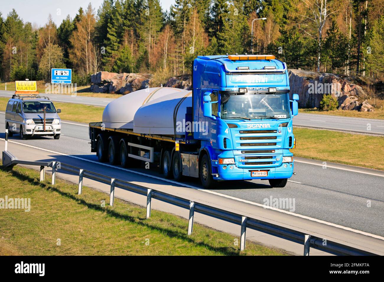 Carrello semirimorchio Blue Scania per il trasporto di oggetti circolari in acciaio sotto forma di carico sovradimensionato, assistito da veicolo di scorta. Salo, Finlandia. 30 aprile 2021. Foto Stock