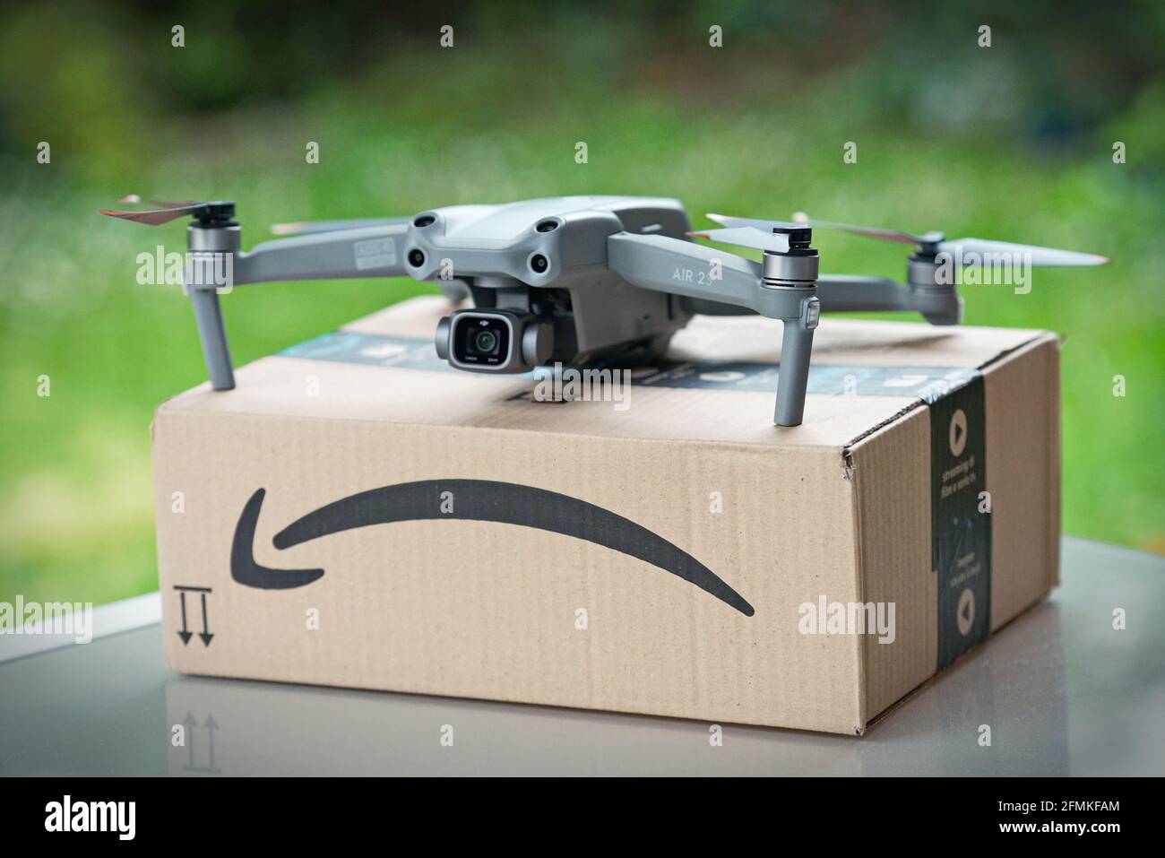 Focus selettivo sul drone che consegna il pacco con il logo amazon su cartone. Milano, Italia - Maggio 2021 Foto Stock