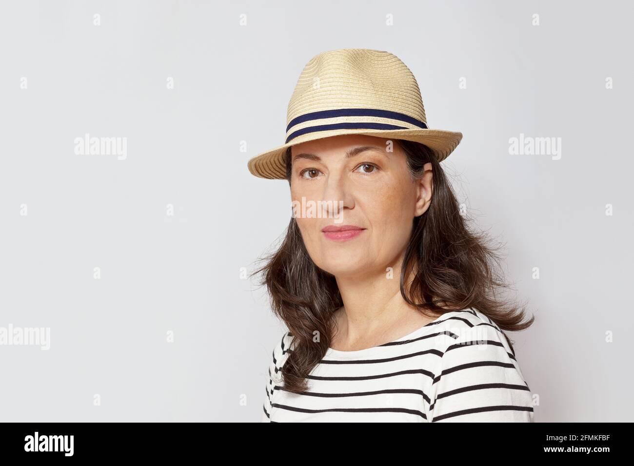Ritratto o headshot di una donna di mezza età molto felice con lunghi capelli marroni, sfondo bianco. Foto Stock