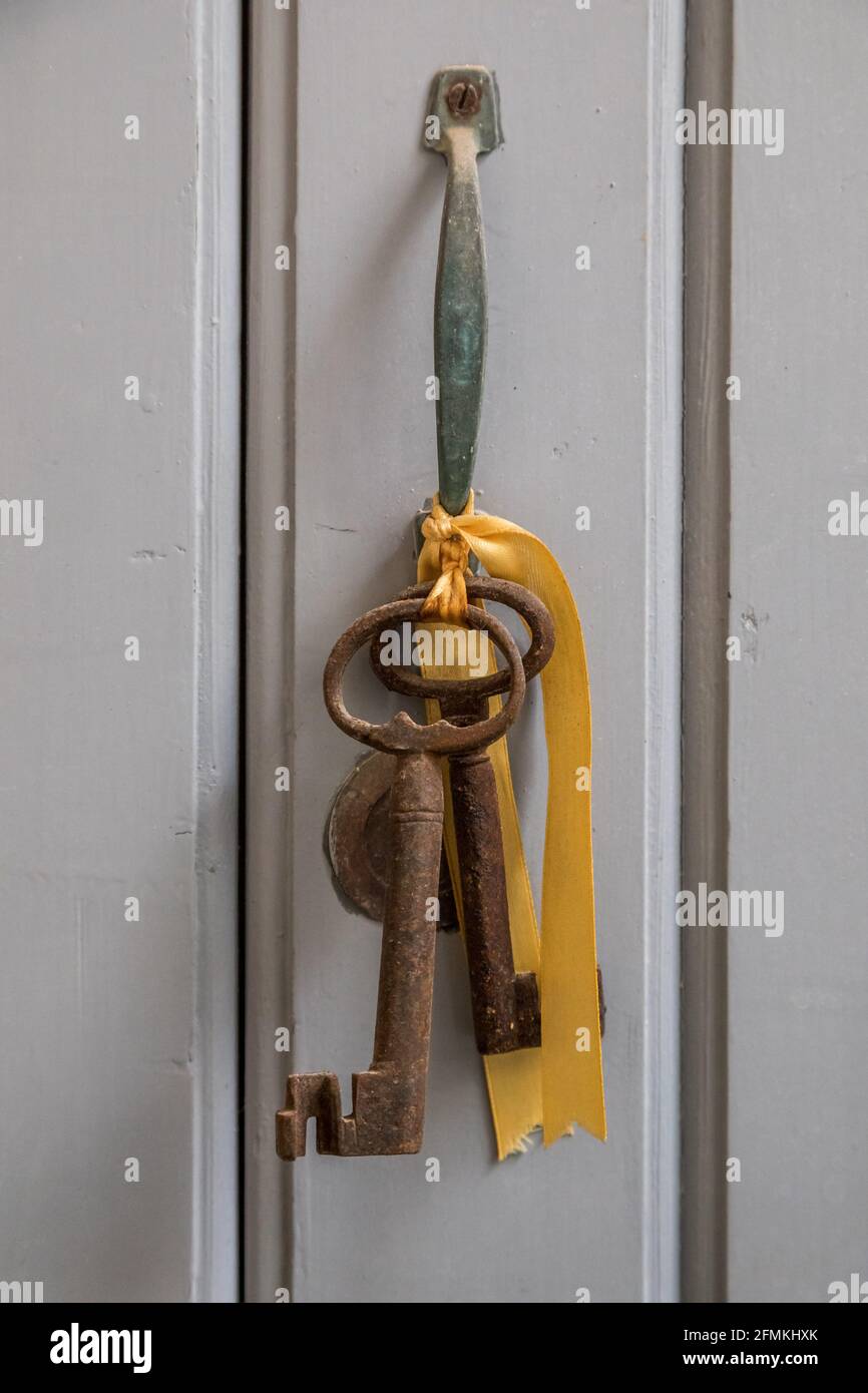 Chiavi della casa, vecchie chiavi della casa d'epoca appese alla maniglia della porta con un nastro giallo dorato Foto Stock
