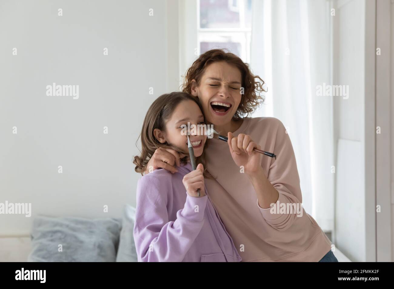 Crazy bonding giovane madre e figlia adolescente canti canzoni. Foto Stock