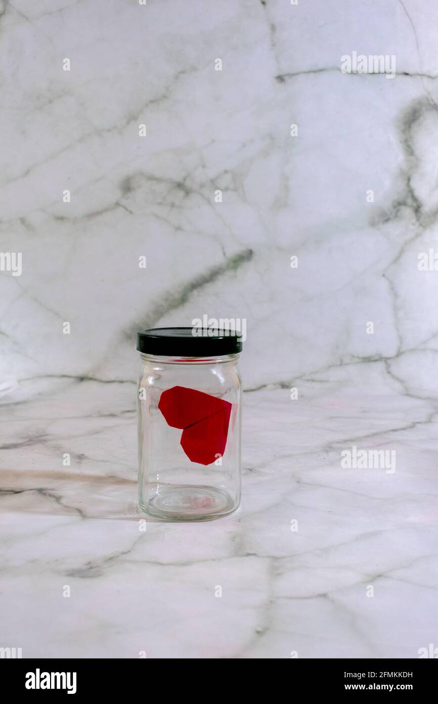Origami cuore all'interno vaso in vetro su sfondo marmorizzato con copia spazio Foto Stock