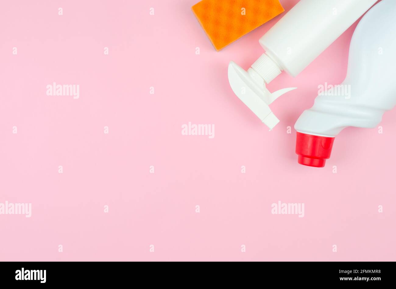 Bottiglie bianche con detergenti e prodotti per la pulizia e una spugna su sfondo rosa con posto per il testo. Prodotti per la pulizia su sfondo rosa. Foto Stock