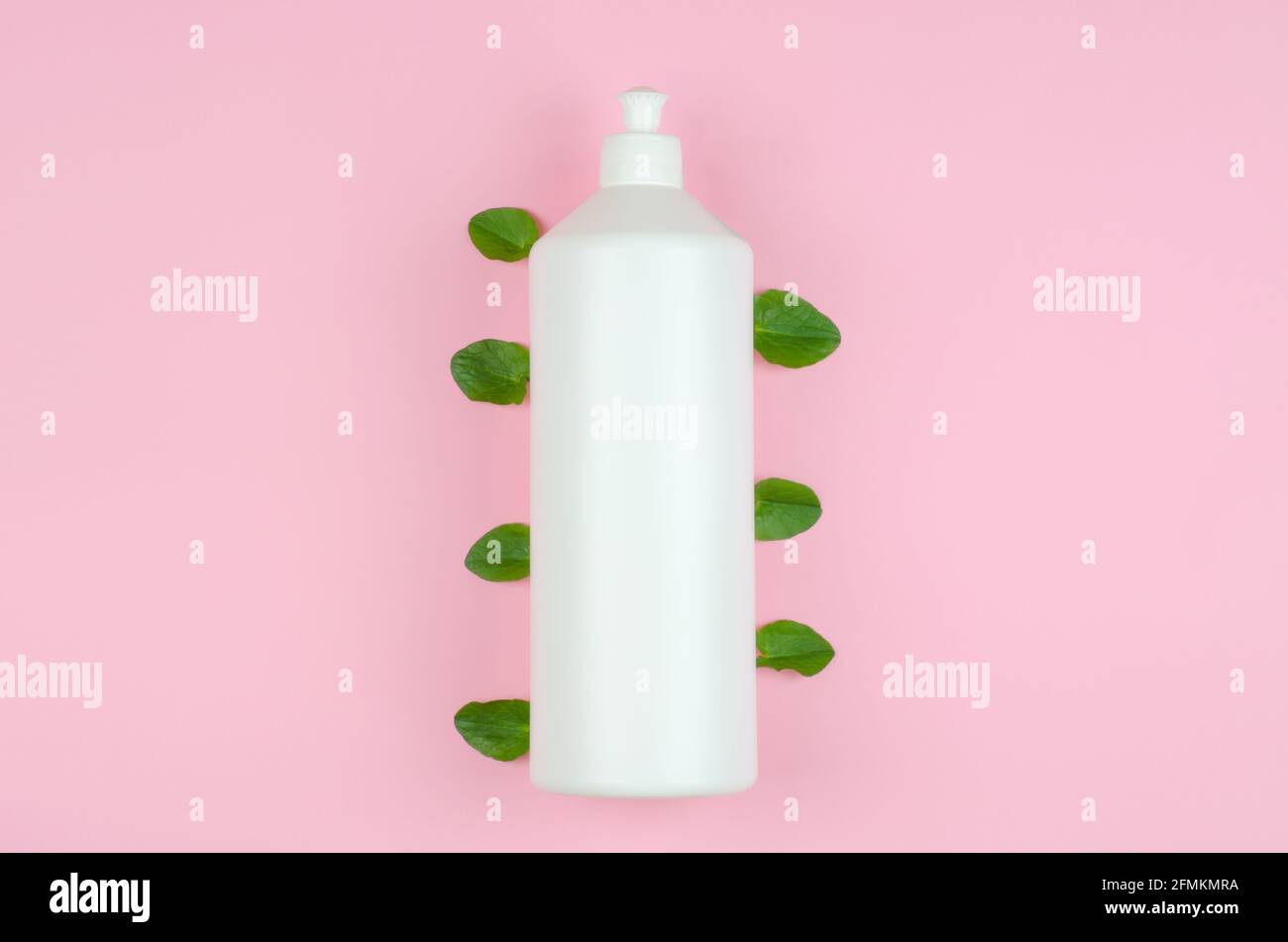 Prodotti per la pulizia ecocompatibili con ingredienti naturali. Bottiglia bianca con detergente e foglie verdi su fondo rosa Foto Stock