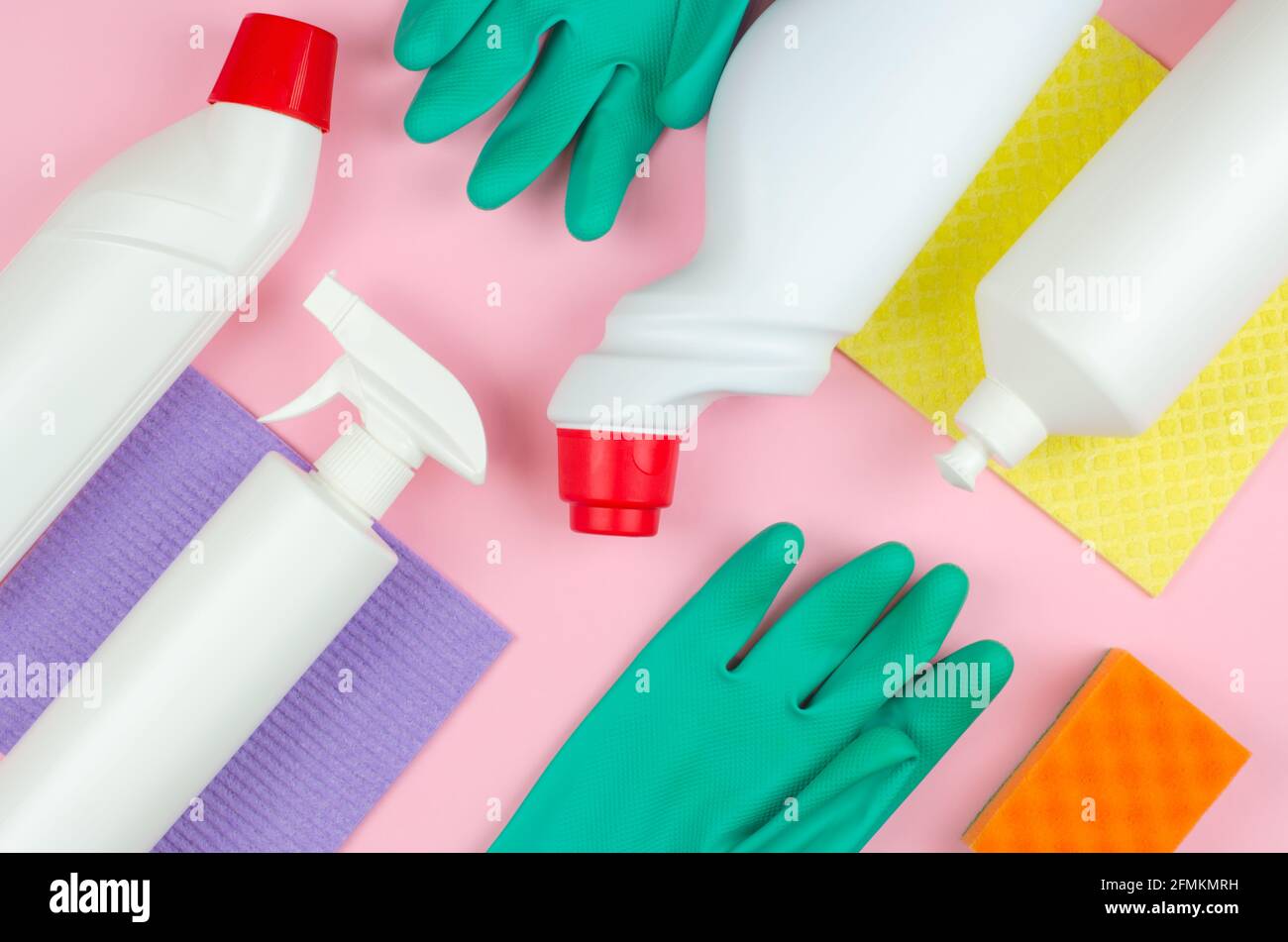 Concetto aziendale di utensili per la pulizia. Bottiglie bianche con detergenti e prodotti per la pulizia e una spugna su fondo rosa. Prodotti per la pulizia Foto Stock