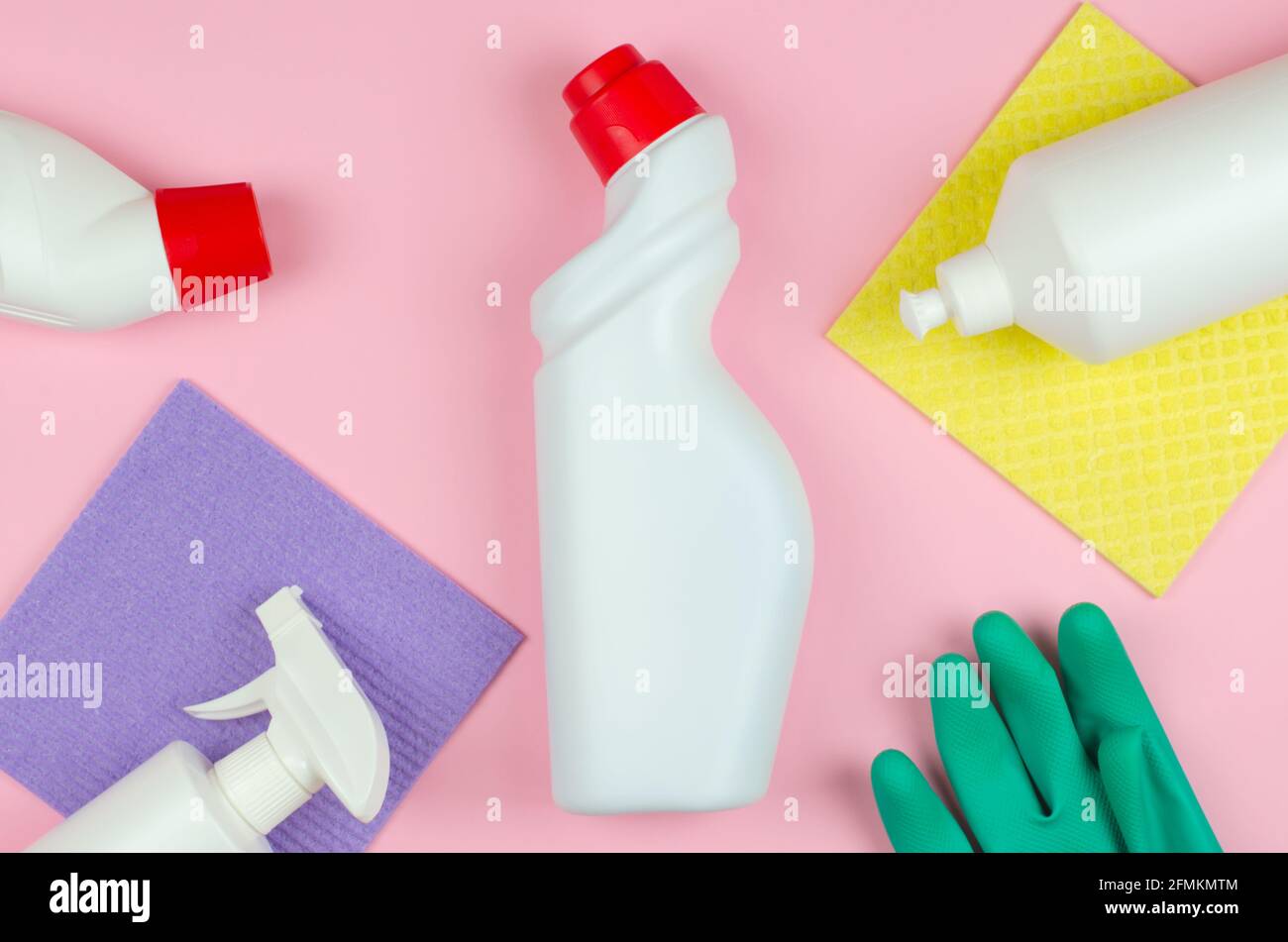 Concetto aziendale di utensili per la pulizia. Bottiglie bianche con detergenti e prodotti per la pulizia e una spugna su fondo rosa. Prodotti per la pulizia Foto Stock