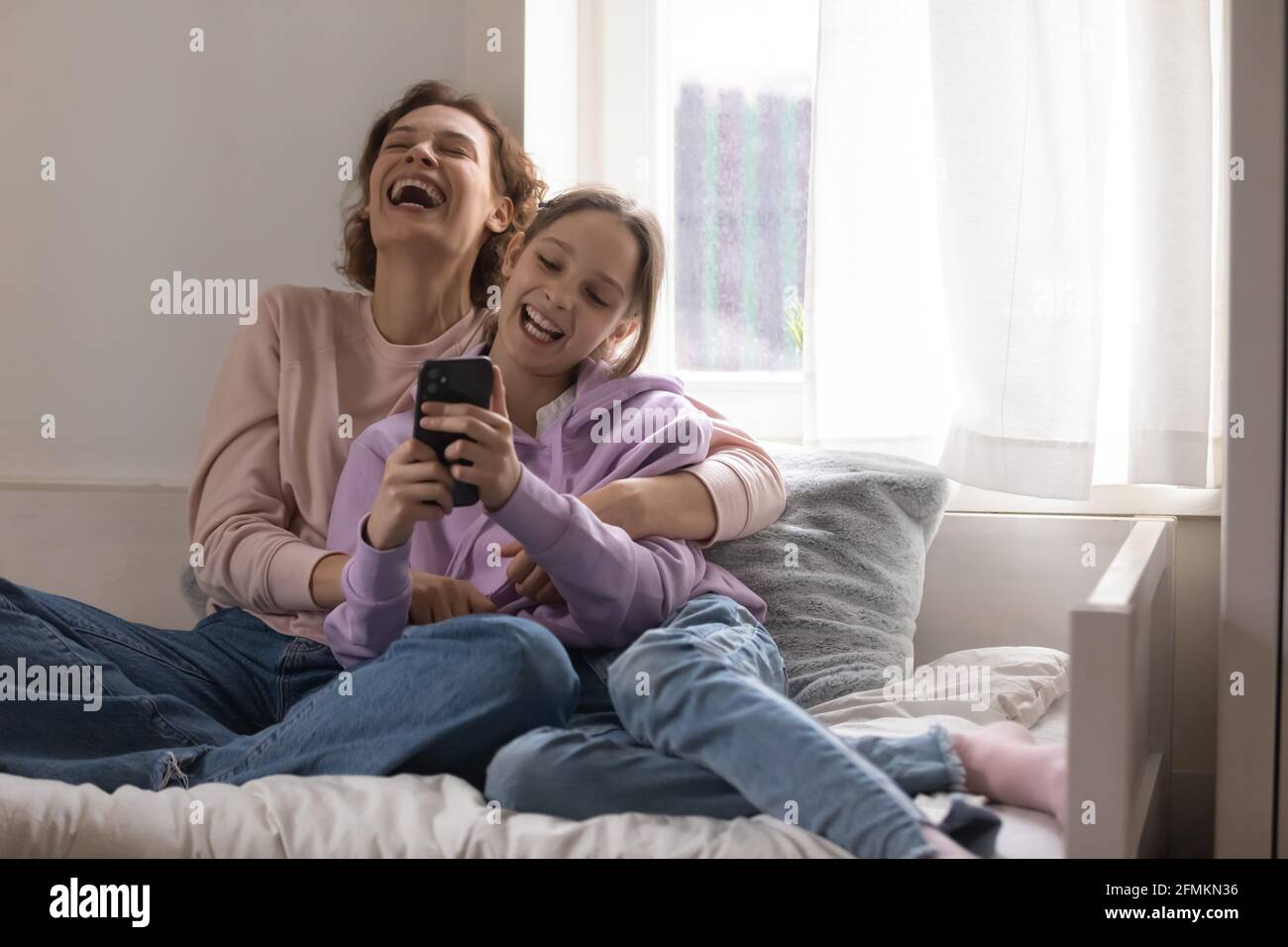 Bonding madre felice e figlia teen ridendo a video divertente. Foto Stock