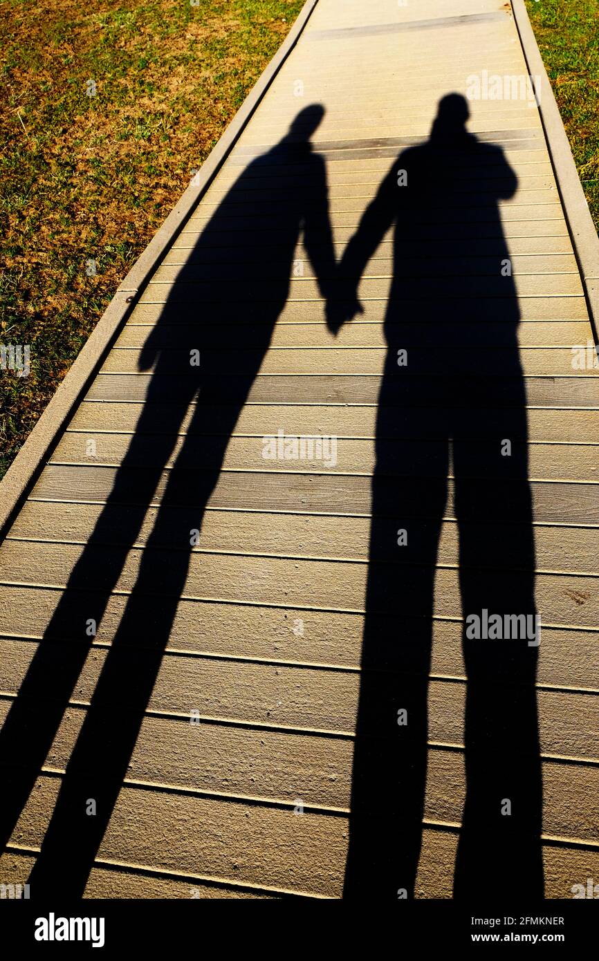Ombra di coppia che tiene le mani sull'amore del marciapiede Foto Stock