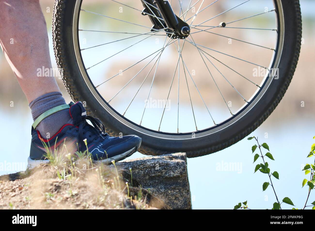 Una ruota di bicicletta si trova su una scogliera sopra la cava, accanto  alla gamba di un uomo. Il ciclista sopra il precipizio. Sport estivi Foto  stock - Alamy