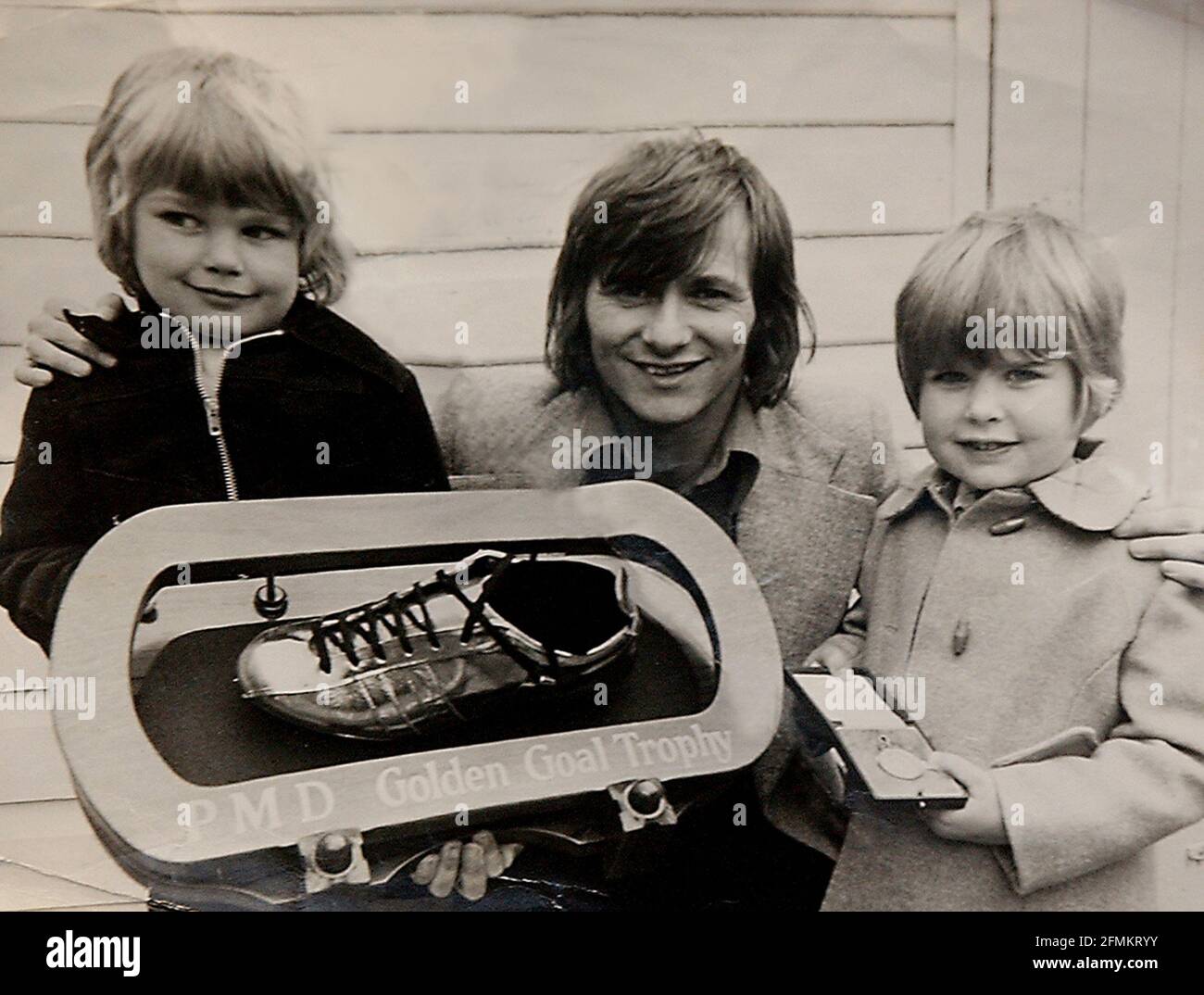 L'OBIETTIVO DI SOUTHAMPTON HERO BOBBY STOKES MOSTRA LA MEDAGLIA DEI SUOI VINCITORI E GOLDEN GOAL TROPHY AI SUOI AMICI FIGLI JAMES (5) E ALLISON (4) WALKER . PIC MIKE WALKER, 1976 Foto Stock