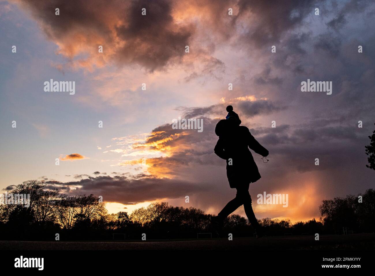 Una ragazza cammina a casa al tramonto indossando un cappello da bob Foto Stock