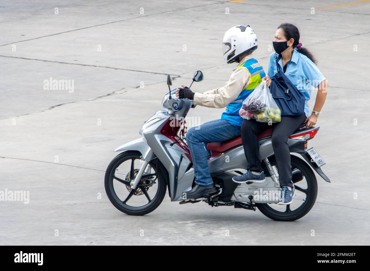 SAMUT PRAKAN, THAILANDIA, 27 2020 LUGLIO, un tassista su una moto giri con una donna. Il conducente del mototaxi trasporta un passeggero. Foto Stock