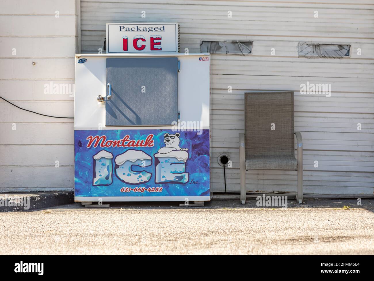La vita still consisteva di una macchina del ghiaccio e di una sedia seduta fuori di una stazione di servizio a Montauk, NY Foto Stock