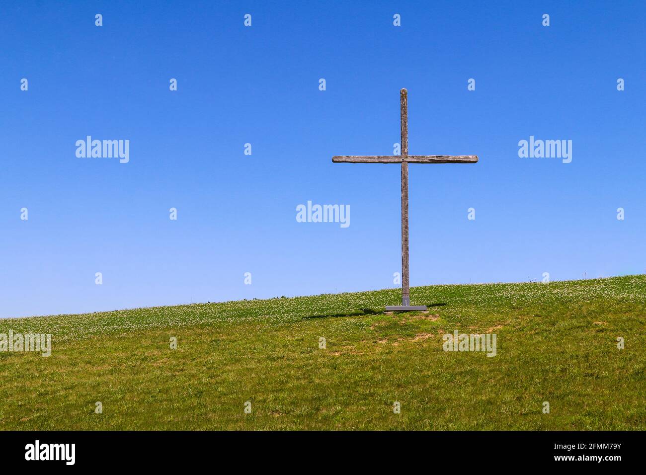 grande croce di legno simbolo cristiano in piedi su una collina erba o collina erbosa rurale come un paesaggio naturale sfondo religioso Foto Stock