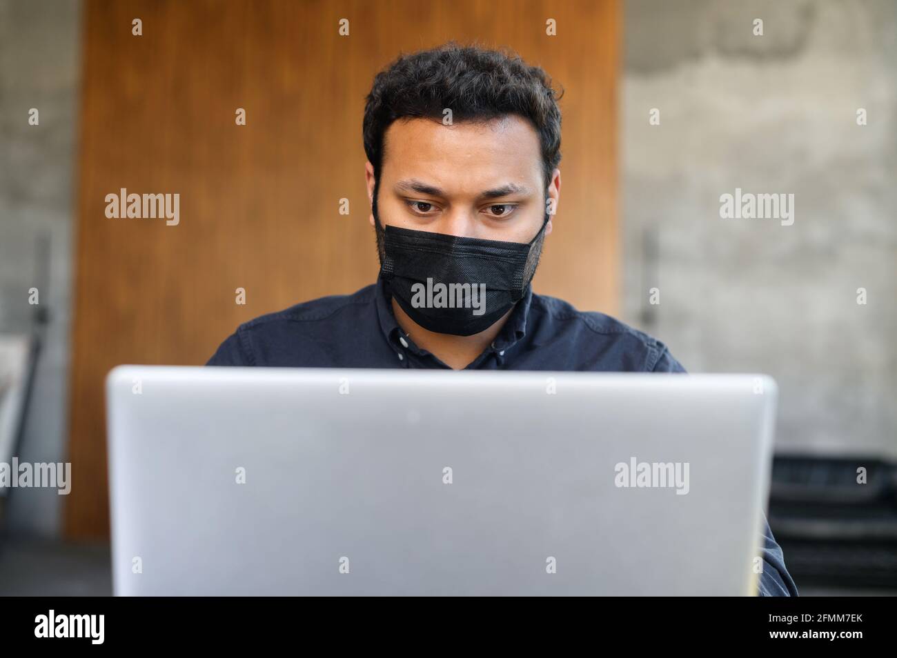 Headshot di uomo indù concentrato indossando maschera medica funziona con un computer portatile in ufficio. Il lavoratore maschile rimane al sicuro durante il periodo pandemico Foto Stock Headshot di uomo indù concentrato indossando maschera medica funziona con un computer portatile in ufficio. Il lavoratore maschile rimane al sicuro durante il periodo pandemico Foto Stock