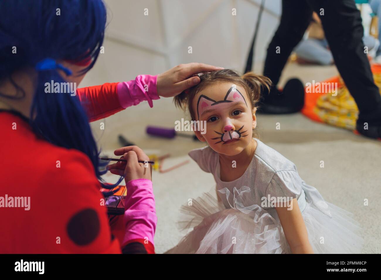 Bambina che ottiene la sua faccia dipinta in forma di farfalla da artista di pittura di faccia. Make up. Persone reali. Spazio di copia Foto Stock