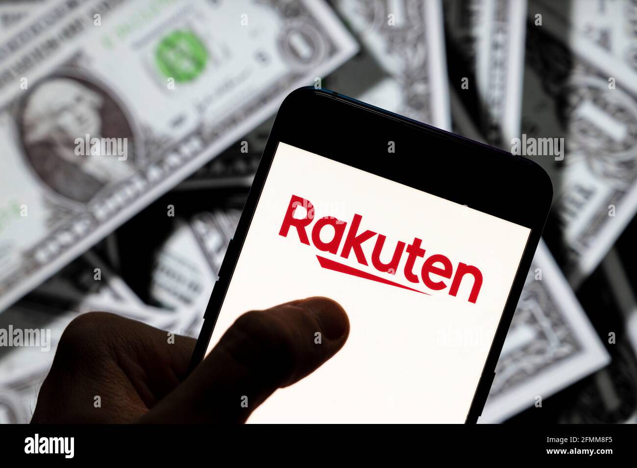 In questa illustrazione della foto il commercio elettronico giapponese e il logo della società di Internet Rakuten visto su uno smartphone con la valuta USD (dollaro degli Stati Uniti) in background. Foto Stock