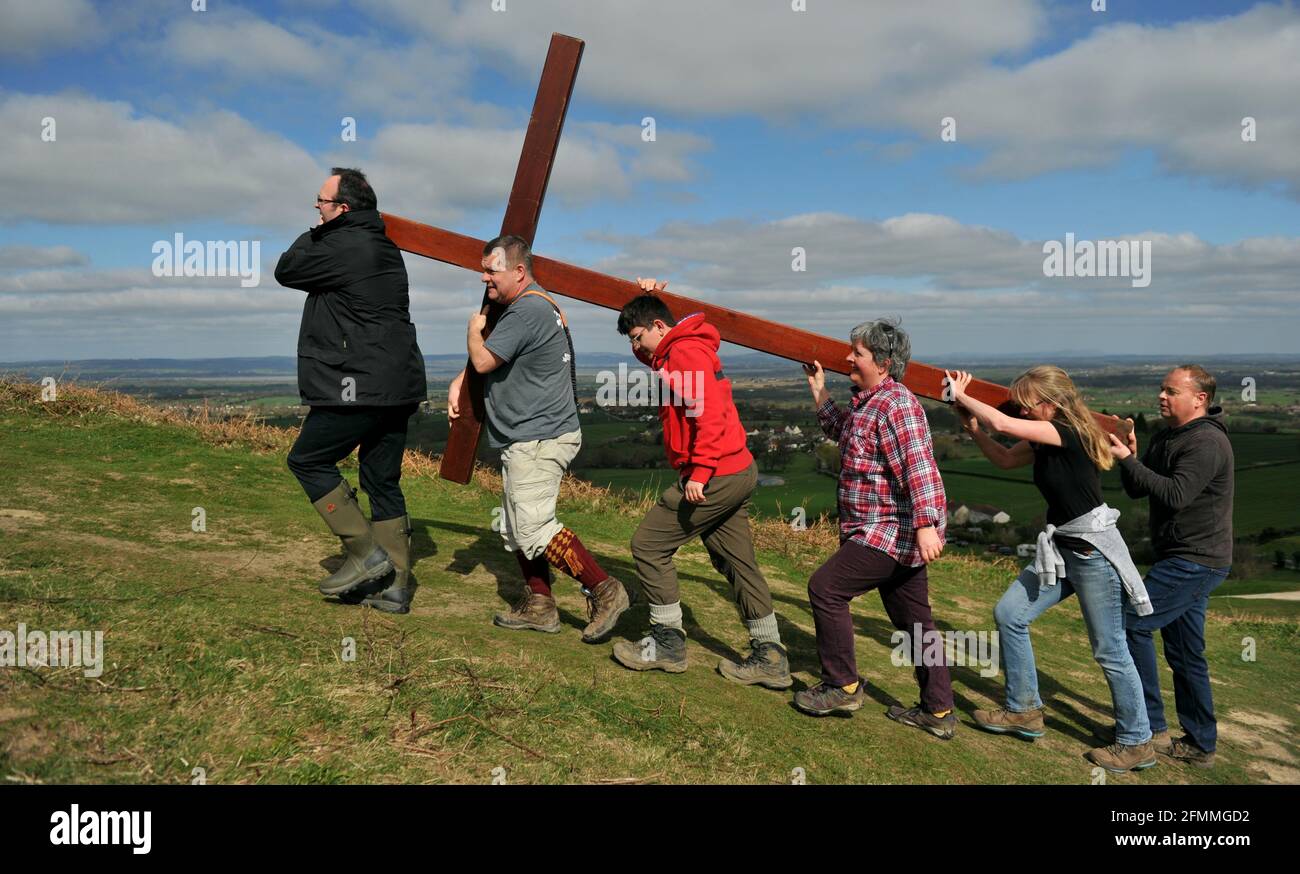 Portando una croce di legno fino Cam Peak il Venerdì Santo prima della Domenica di Pasqua in una passeggiata di testimone, Gloucestershire Foto Stock