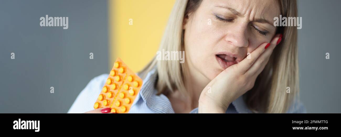 La donna soffre di mal di denti e tiene le pillole nelle mani Foto Stock