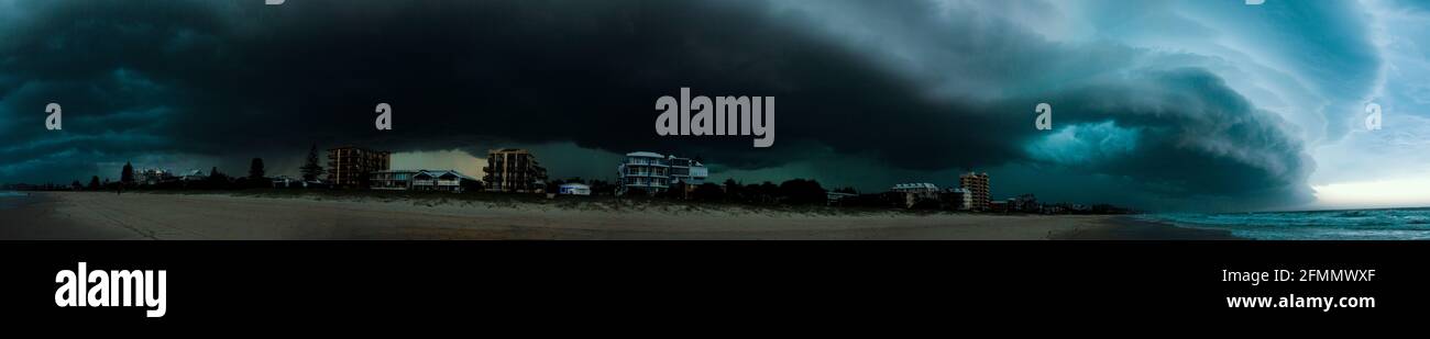 Panorama di enorme cella di tempesta che rotola in sopra un oro Spiaggia costiera Foto Stock