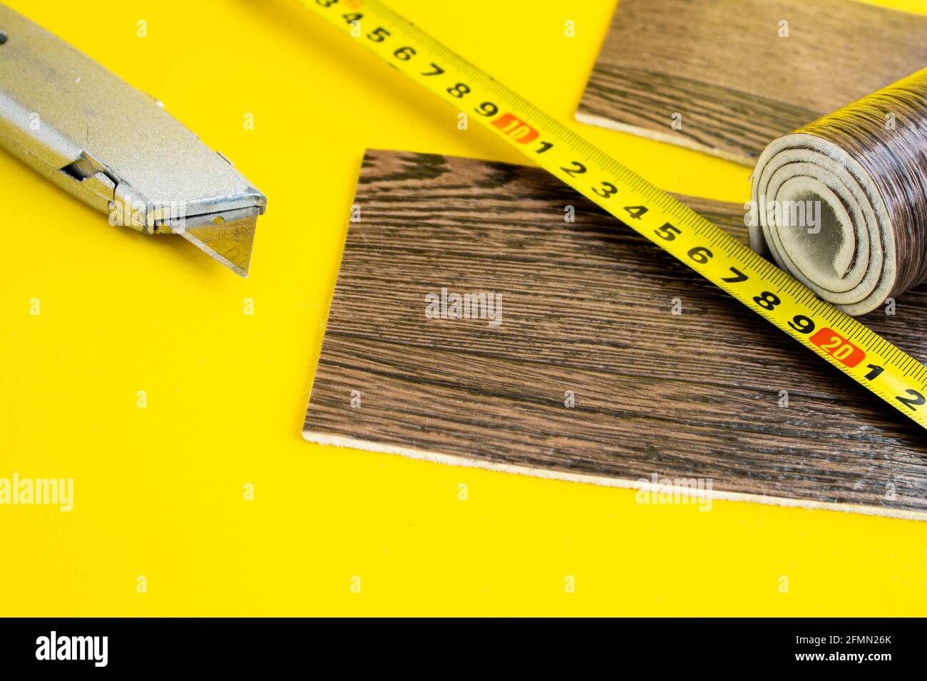 Metro a nastro in linoleum e coltello su fondo isolato. Un pezzo di linoleum. Misurazione e taglio del linoleum. Linoleum per pavimenti in PVC. Galleggiamento domestico Foto Stock