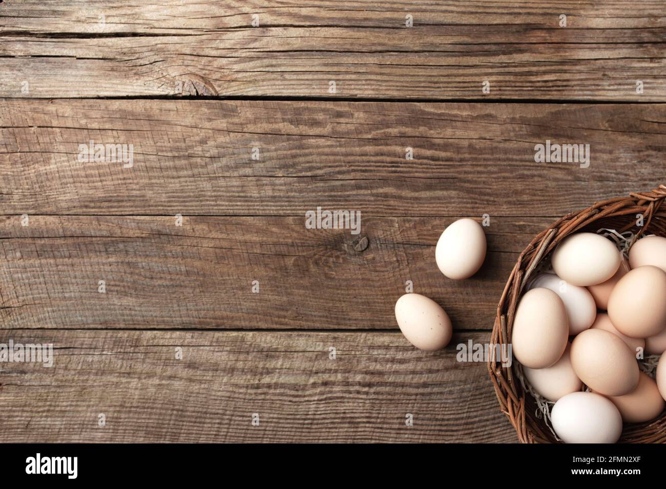 Uova di pollo biologiche in cestino su sfondo di legno. Concetto domestico biologico con uova da galline allevate di free-range e pascolo Foto Stock