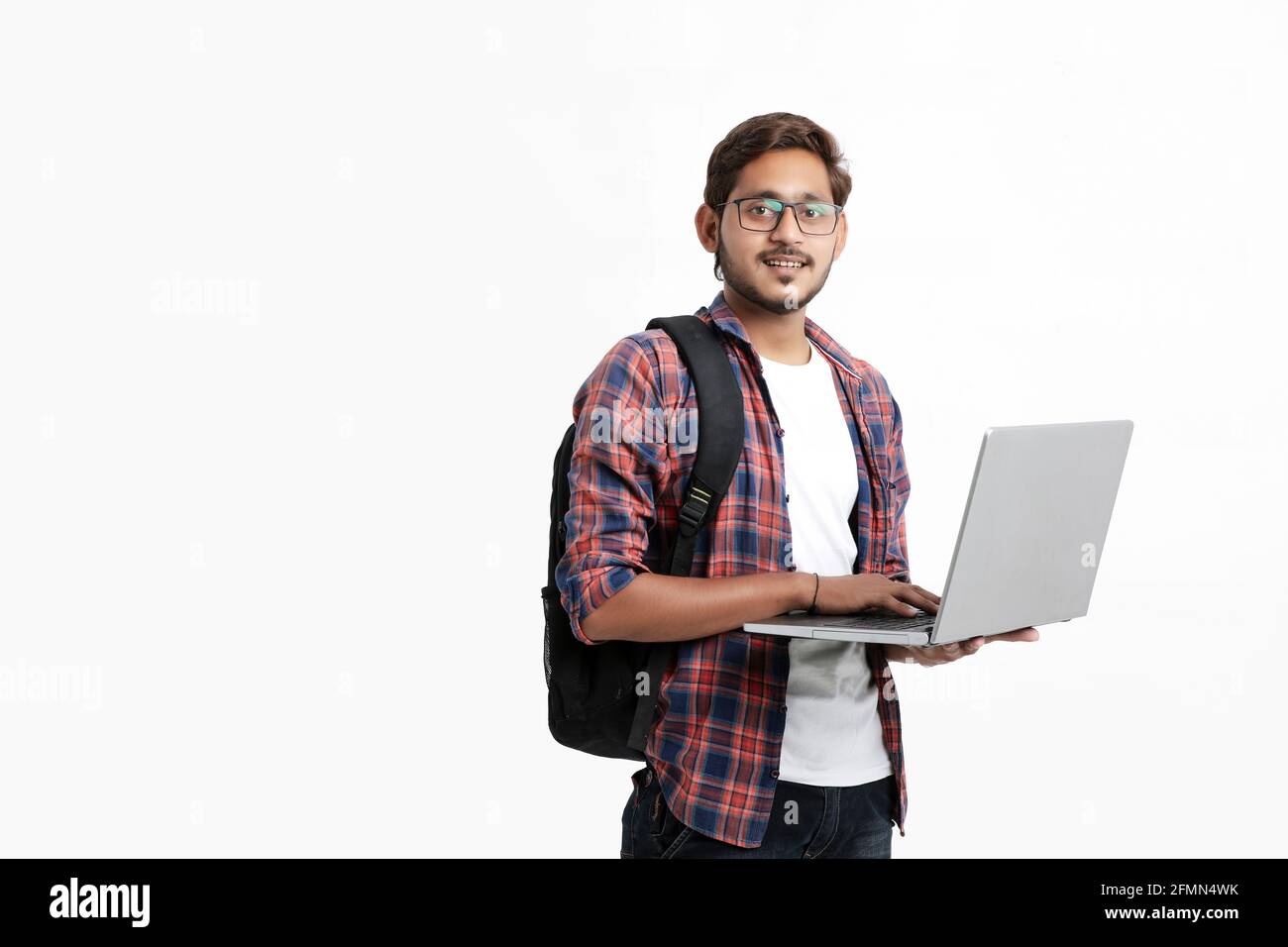 Studente universitario indiano che usa un computer portatile su sfondo bianco. Foto Stock