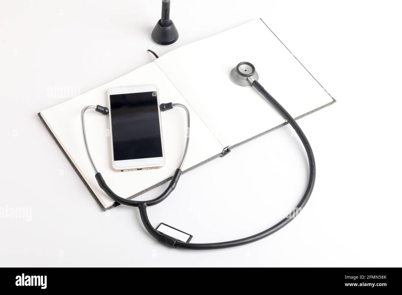 Smartphone e stetoscopio su sfondo bianco. Tecnologia di medicina online (telemedicina). Servizio di diagnostica remota, chat con il medico. Foto Stock
