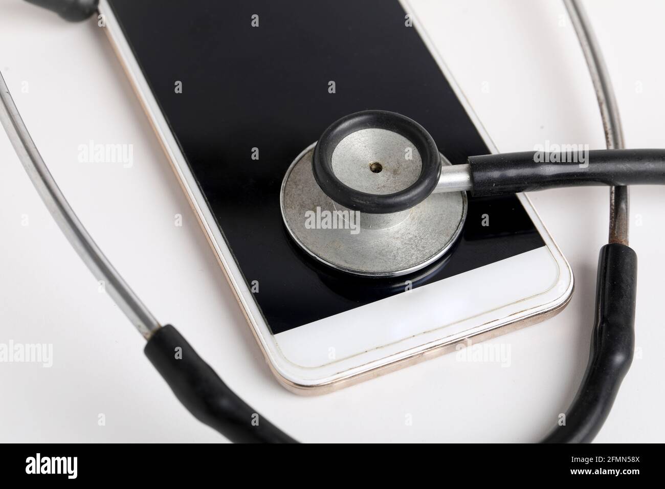 Smartphone e stetoscopio su sfondo bianco. Tecnologia di medicina online (telemedicina). Servizio di diagnostica remota, chat con il medico. Foto Stock