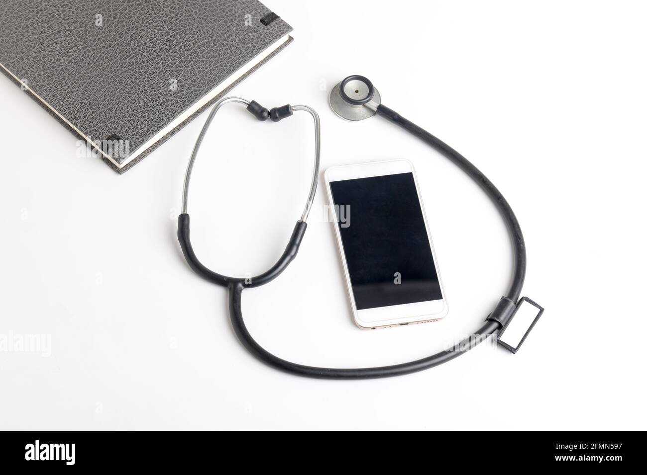 Smartphone e stetoscopio su sfondo bianco. Tecnologia di medicina online (telemedicina). Servizio di diagnostica remota, chat con il medico. Foto Stock