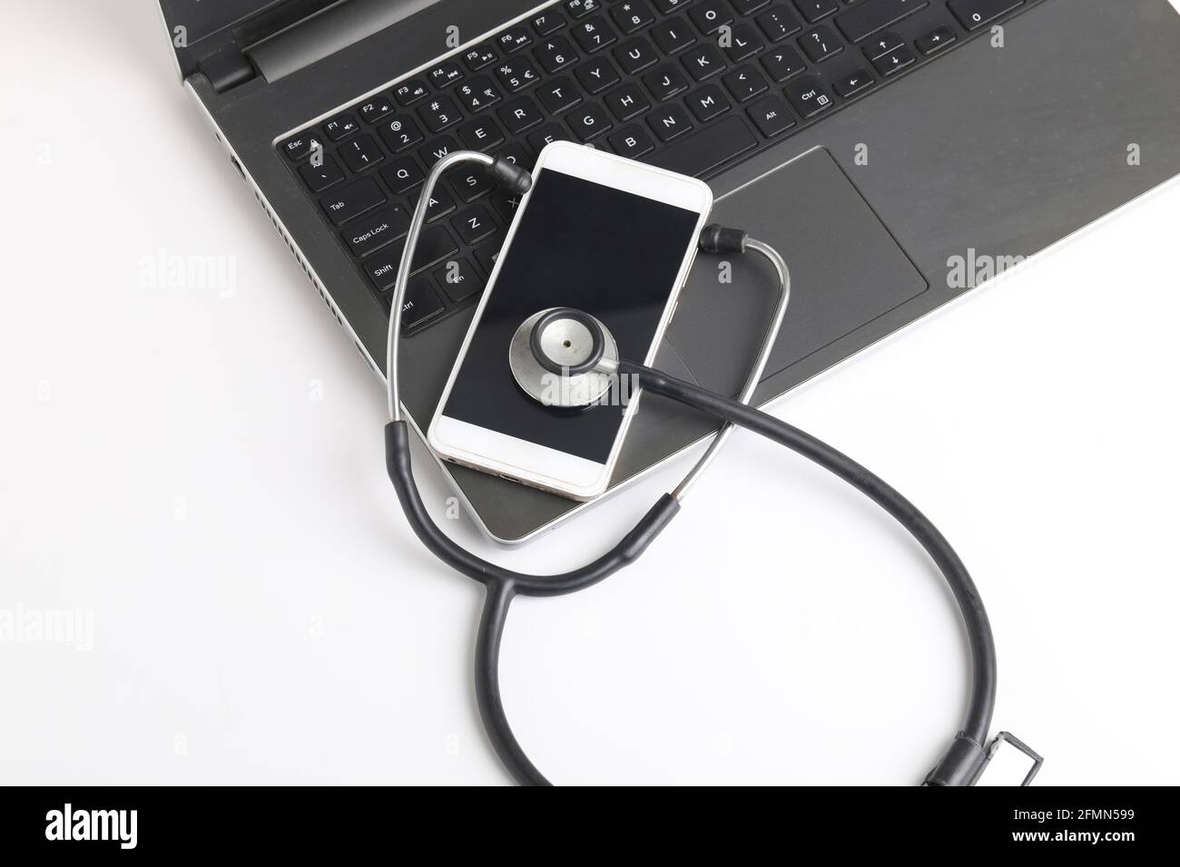 Luogo di lavoro del medico con computer portatile e stetoscopio e smartphone su tavolo bianco foto vista dall'alto. Foto Stock