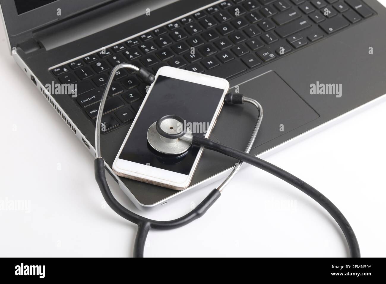 Luogo di lavoro del medico con computer portatile e stetoscopio e smartphone su tavolo bianco foto vista dall'alto. Foto Stock