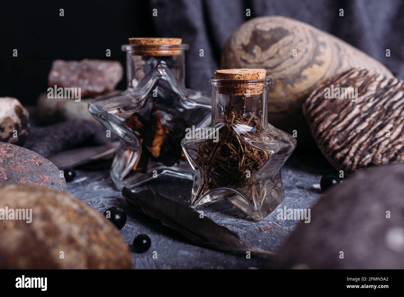 Le bottiglie di vetro sono riempite con ingredienti magici. Tavolo delle streghe, pietre. Foto Stock