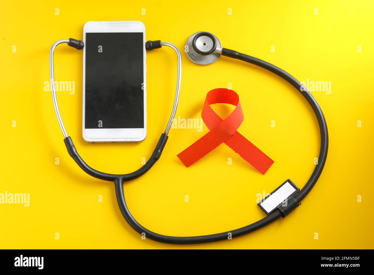 Smartphone e stetoscopio su sfondo giallo. Tecnologia di medicina online (telemedicina). Servizio di diagnostica remota, chat con il medico. Foto Stock