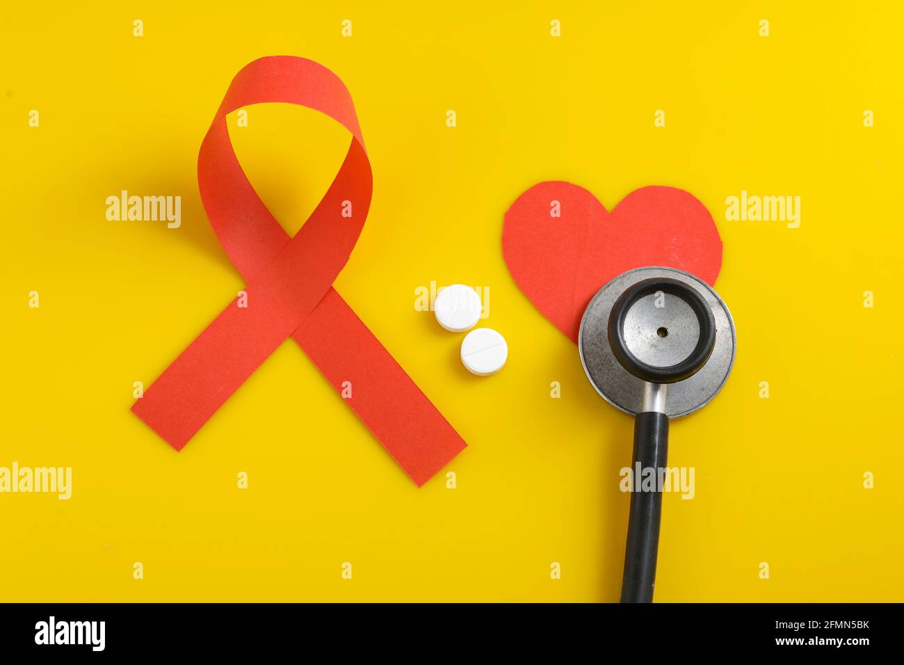 Posto di lavoro del medico con stetoscopio, compresse in blister, siringa su sfondo giallo. Foto Stock