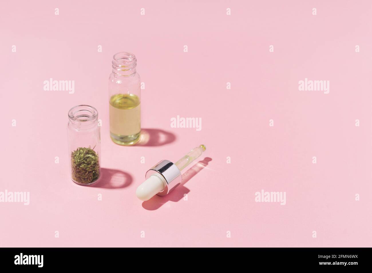 Due vasetti con cannabis secca e olio su rosa pastello sfondo Foto Stock