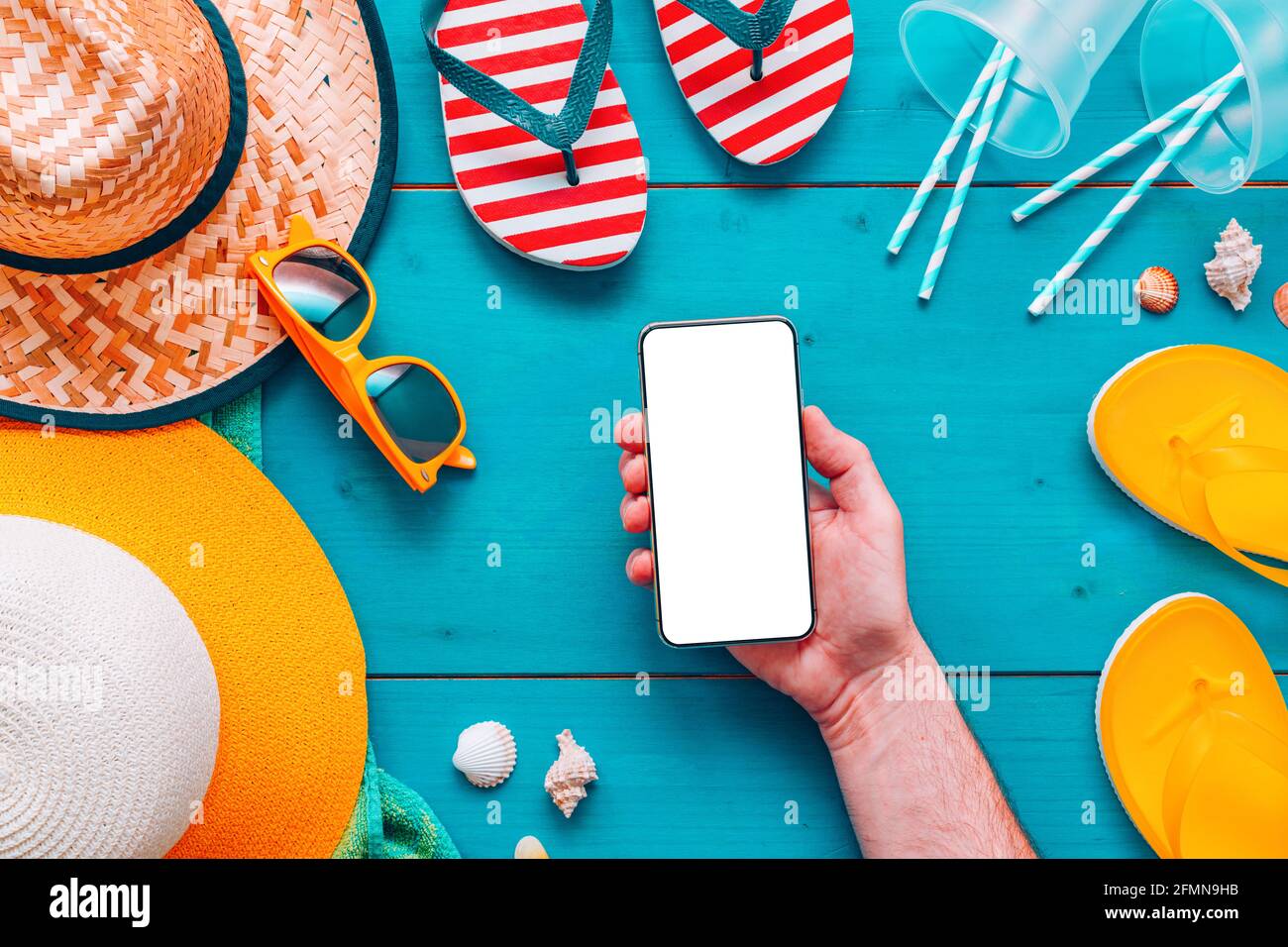 Smartphone mock-up in mano maschile per vacanze estive concetto di vacanza, touch screen vuoto e accessori spiaggia, piano di vista dall'alto Foto Stock