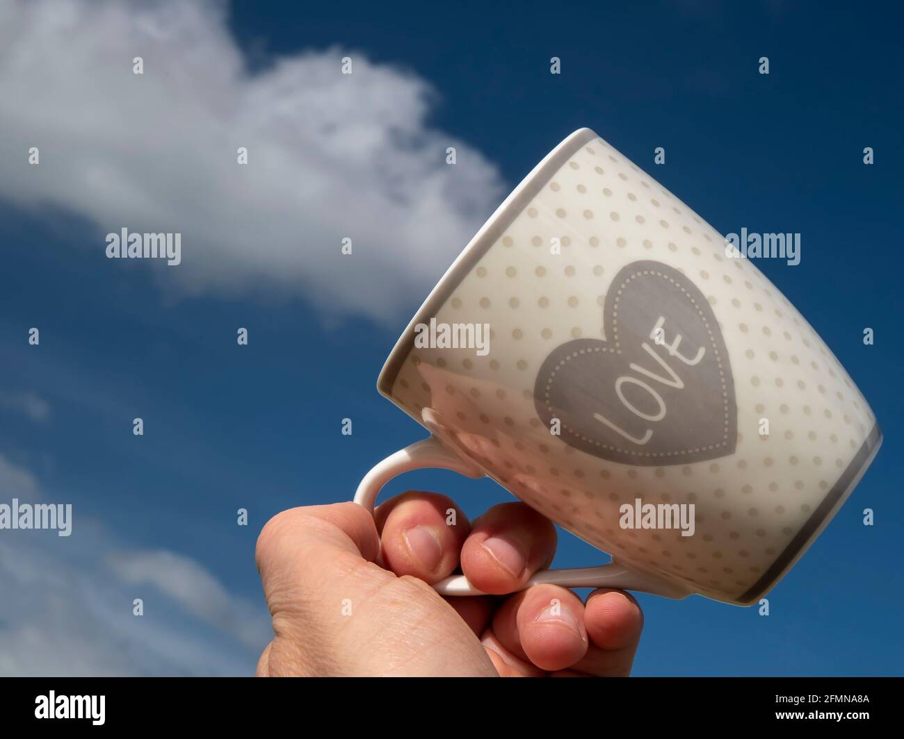 Una mano tiene una tazza in corrispondenza di un bianco nuvola che sembra uscire dalla tazza stessa Foto Stock