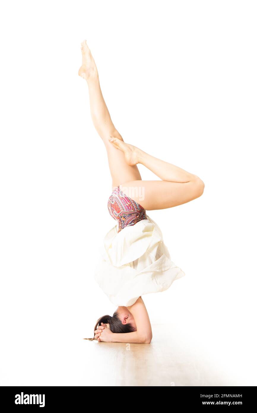Ritratto di giovane donna sportiva attiva che pratica in piedi sulla testa yoga posa in studio yoga. Uno stile di vita sano e attivo Foto Stock
