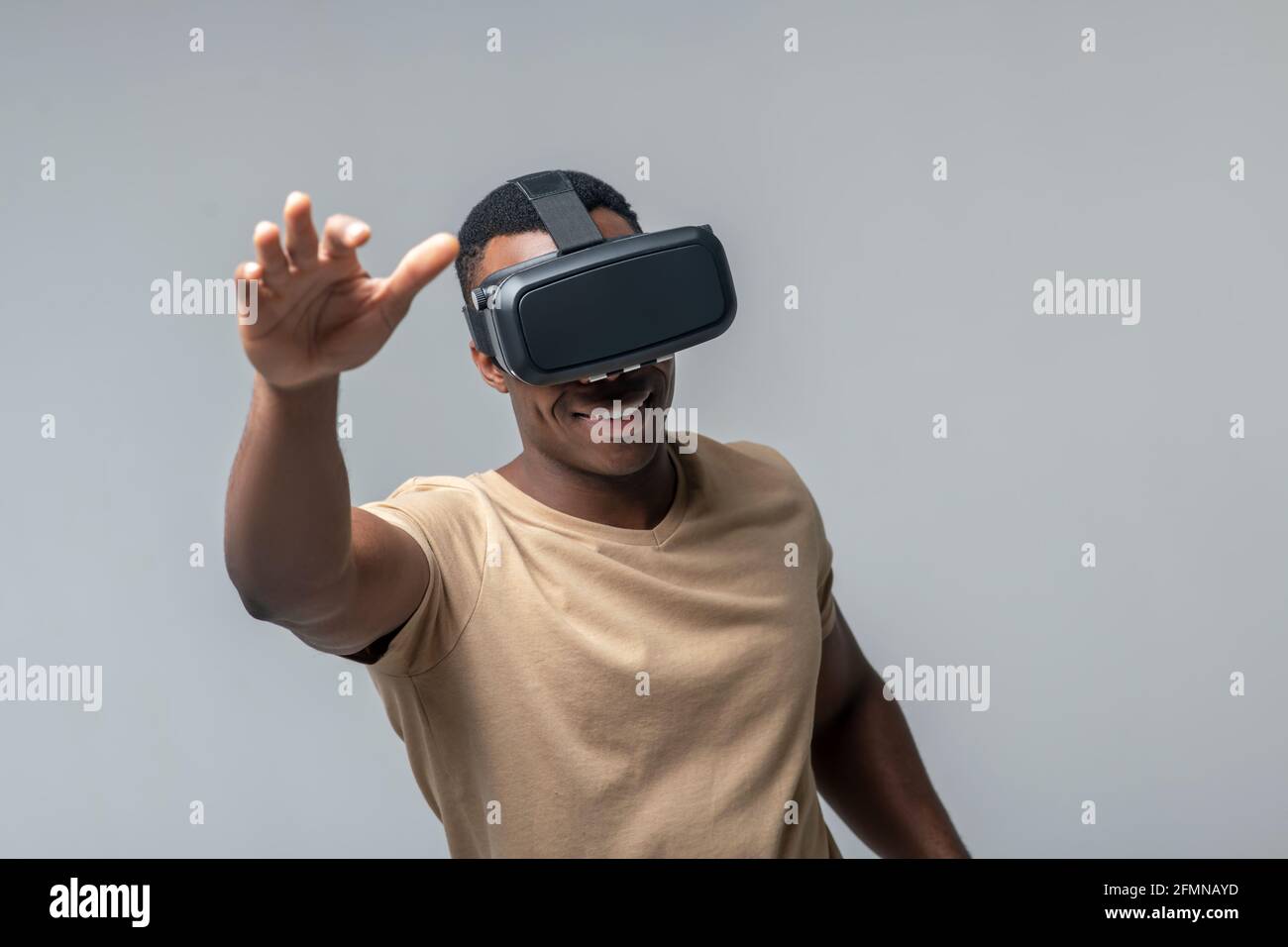 Uomo sorridente in occhiali VR che gli agitando le mani Foto Stock