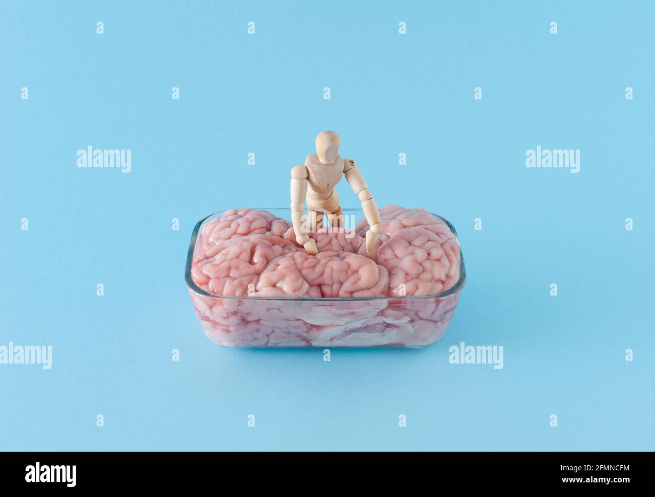 Layout creativo con manichino in legno alla ricerca di problemi nel cervello umano. Malattia del cervello. Concetto di salute mentale in stile minimo. Foto Stock