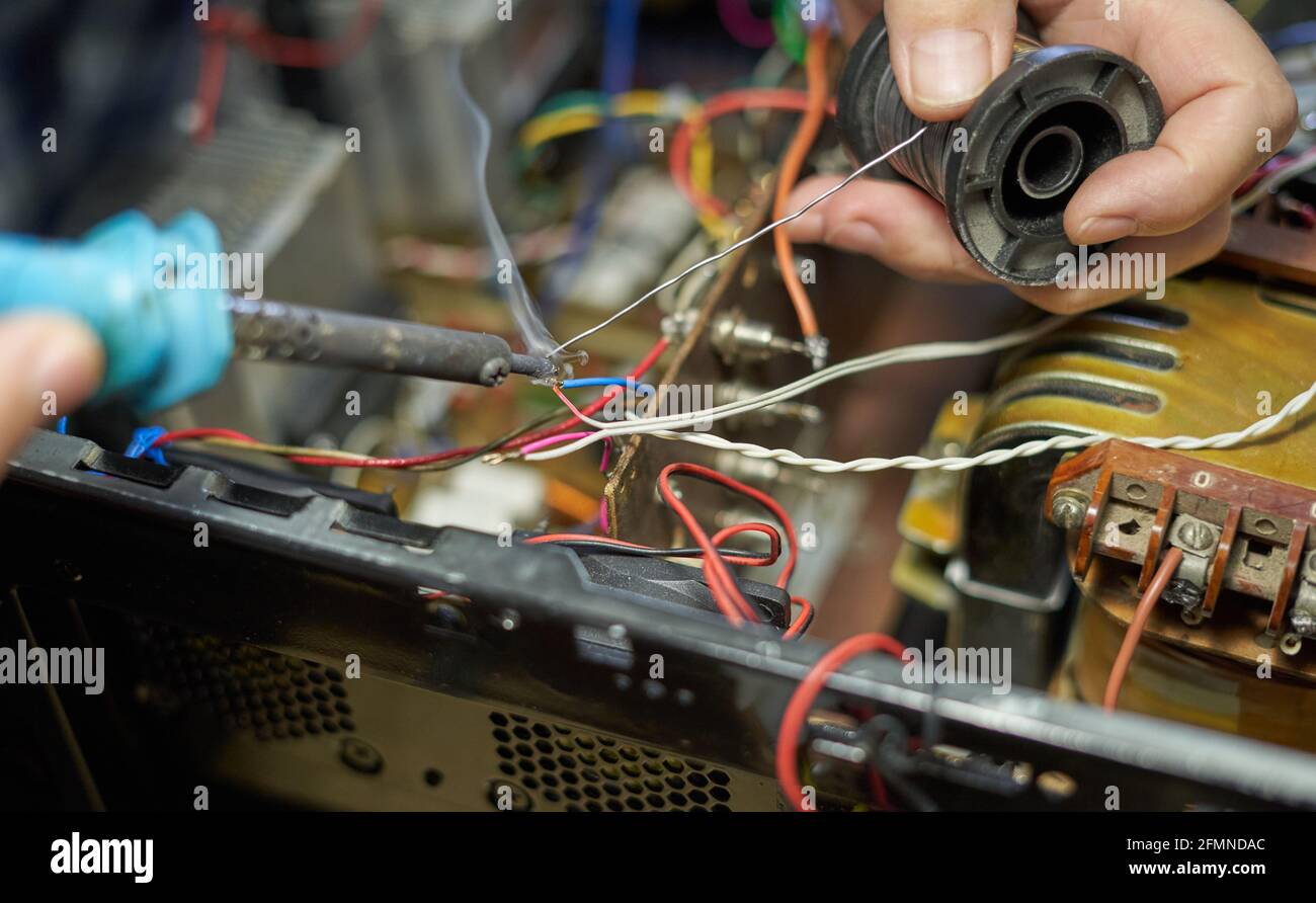 Man saldante i fili durante la riparazione dell'apparecchiatura Foto Stock