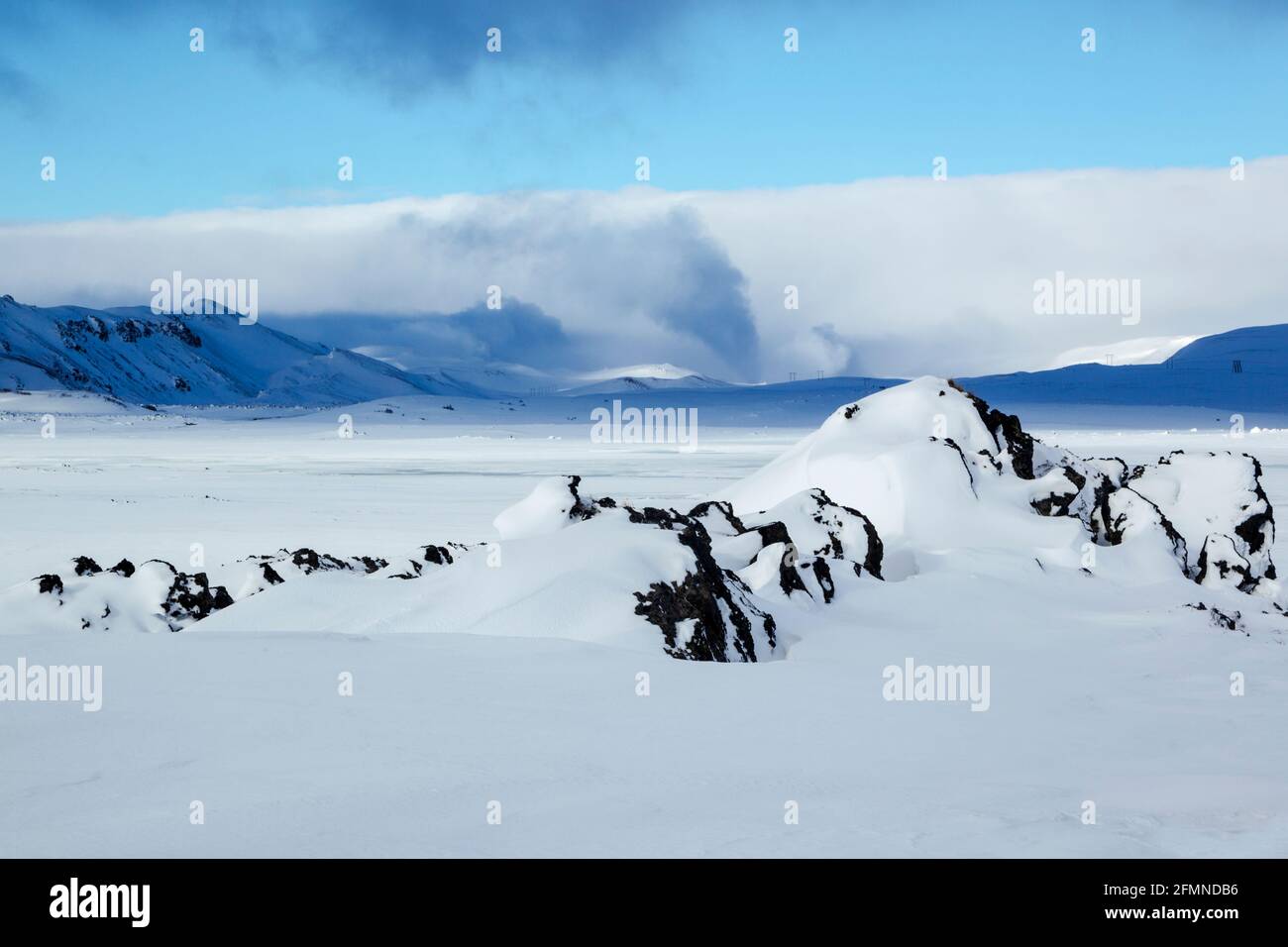Neve e ghiaccio vista invernale attraverso la zona di Burfelshraun vicino Ad Hevrir, nel nord-est dell'Islanda, comprese le linee di alimentazione aeree in distanza Foto Stock