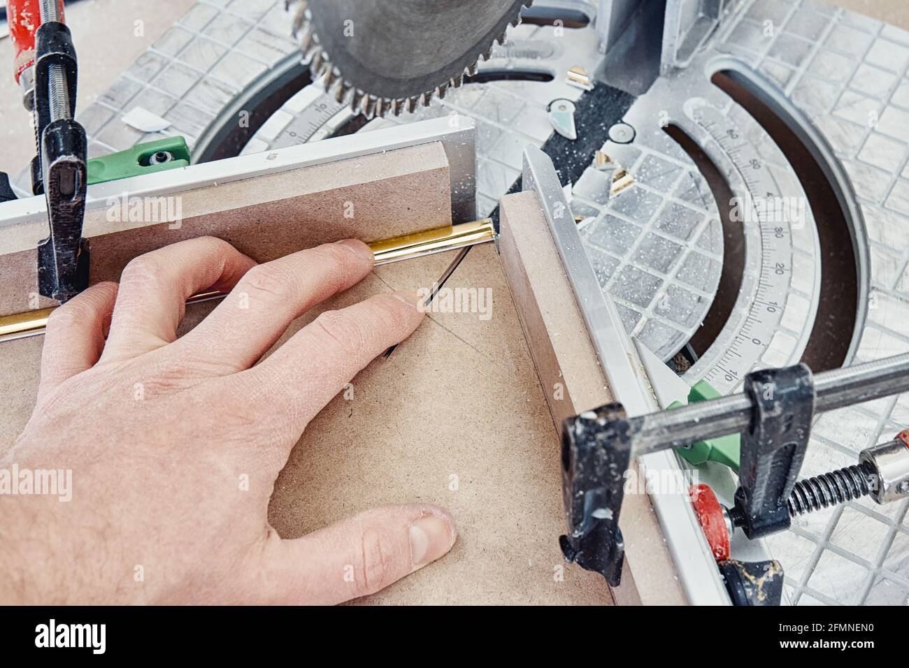 Lavoratore taglio Golden modanatura striscia decorativa per mobili pannello facciata su troncatrice durante il processo di produzione Foto Stock