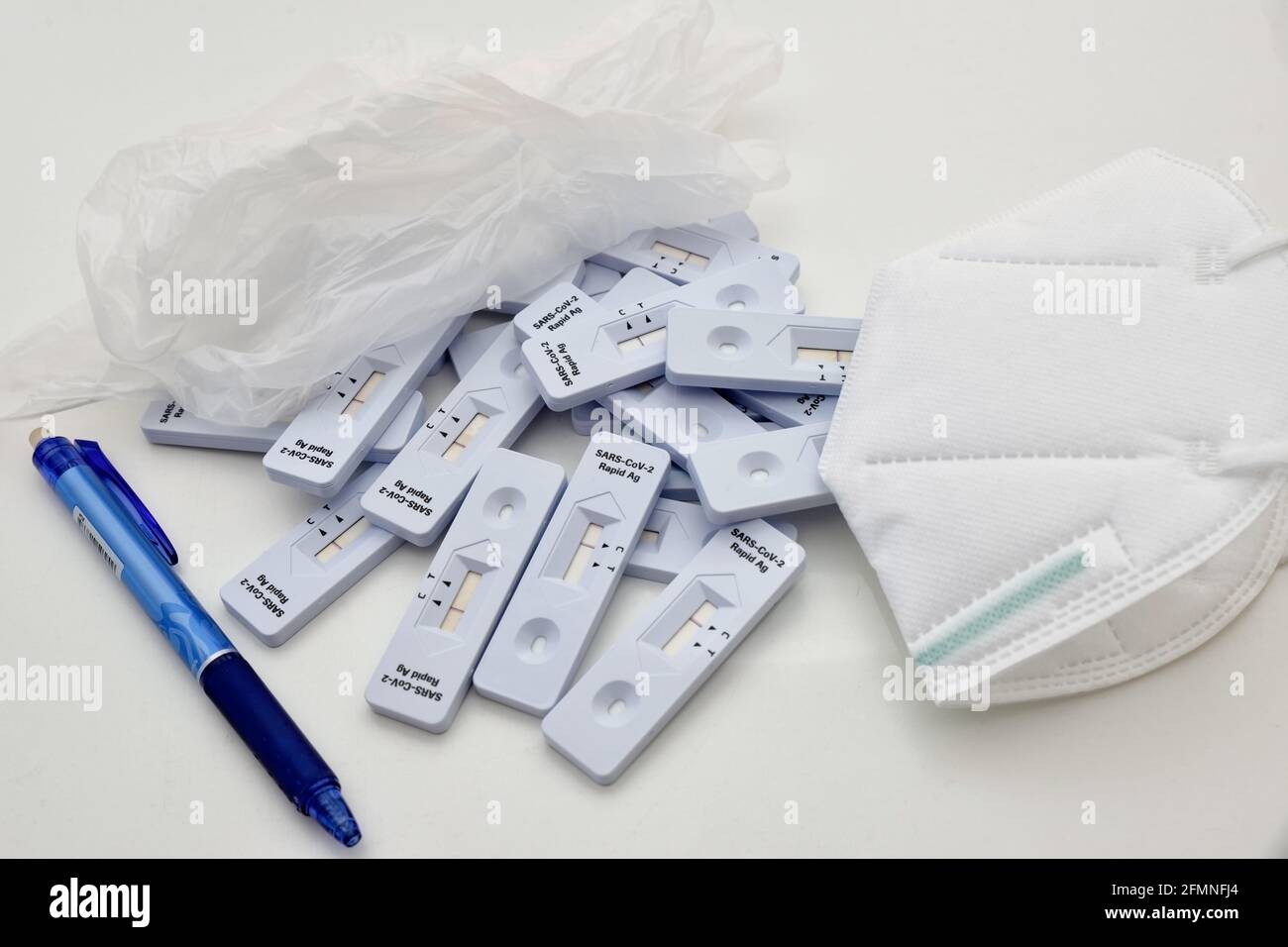 mazzo di kit di test per antigene rapido del virus della coronia che si trova sulla superficie del laboratorio. Con guanti, penna blu e maschera protettiva bianca come medico di ginocchio Foto Stock