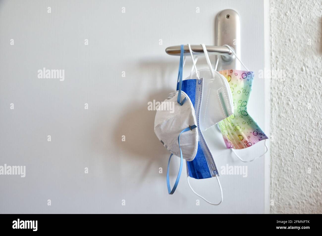 Raccolta di maschere facciali protettive per la malattia da virus corona tutta la famiglia appesa alla porta blu chirurgico colorati bambini bianco ffp2 kn95 Foto Stock