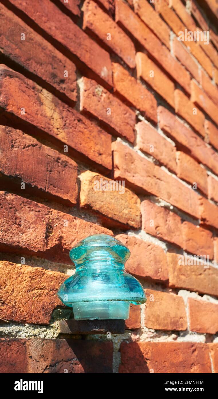 Primo piano immagine di un vecchio isolante elettrico in vetro su un edificio a muro in mattoni, fuoco selettivo. Foto Stock