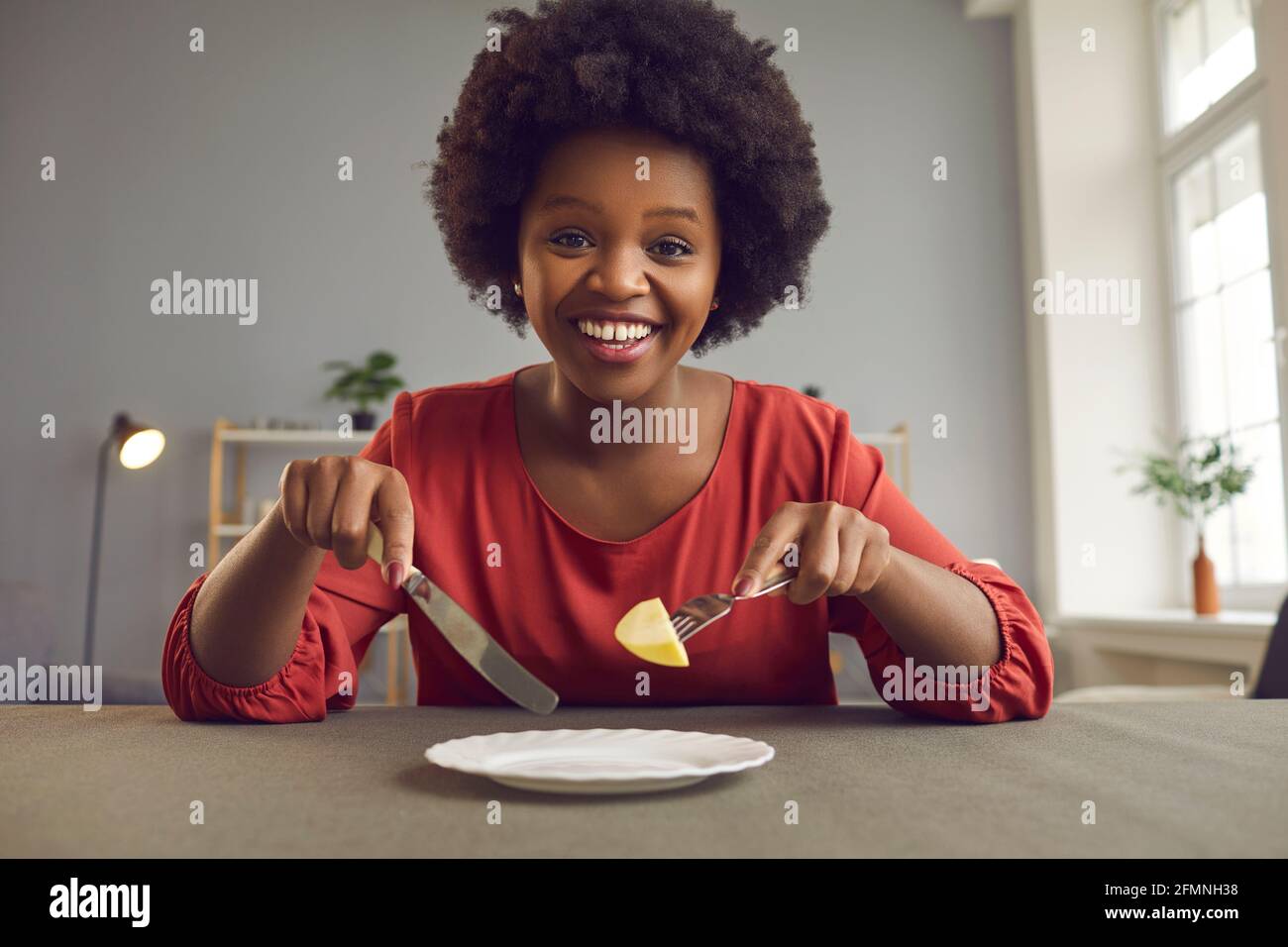 Felice sorridente donna afroamericana sulla dieta che mangia mela cercando alla telecamera Foto Stock