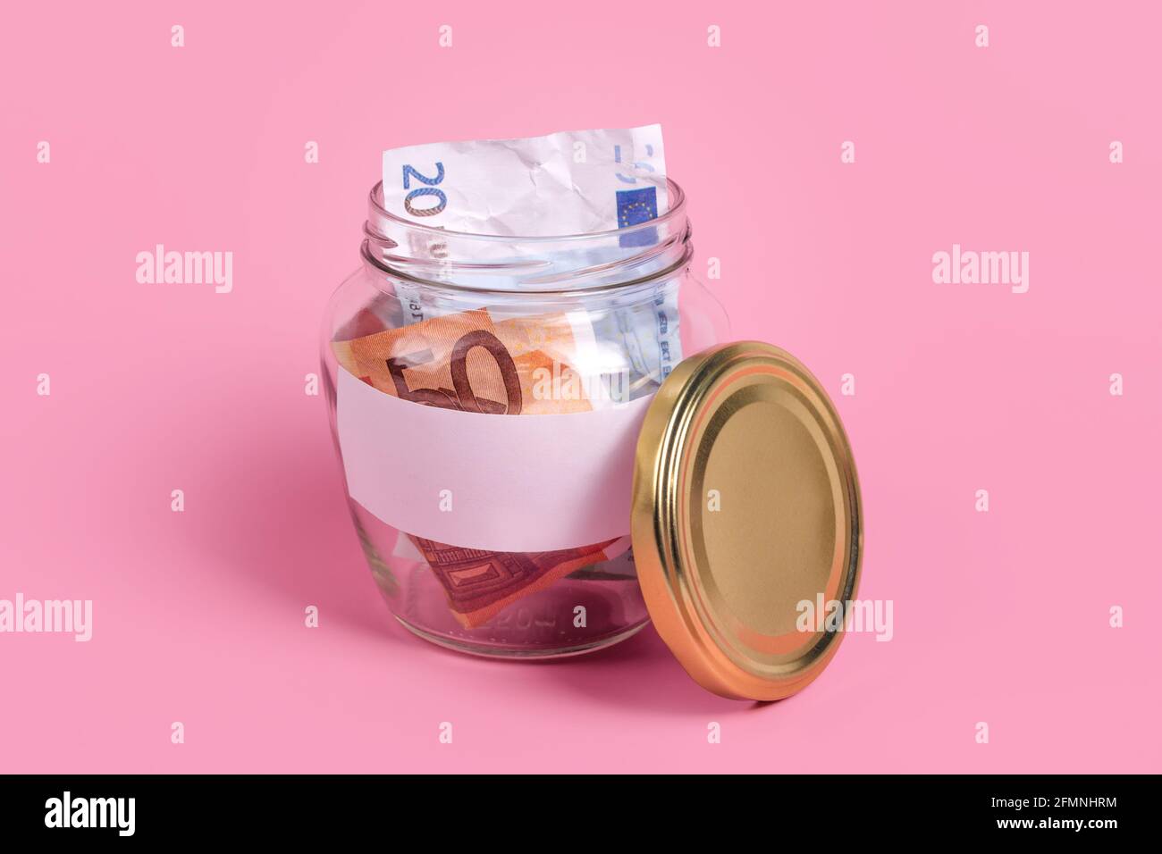 Banconote in euro in vaso di vetro con etichetta vuota, finanziarie, risparmio. Scatola di denaro con carta adesiva vuota. Vaso pieno di contanti, concetto di risparmio di denaro Foto Stock