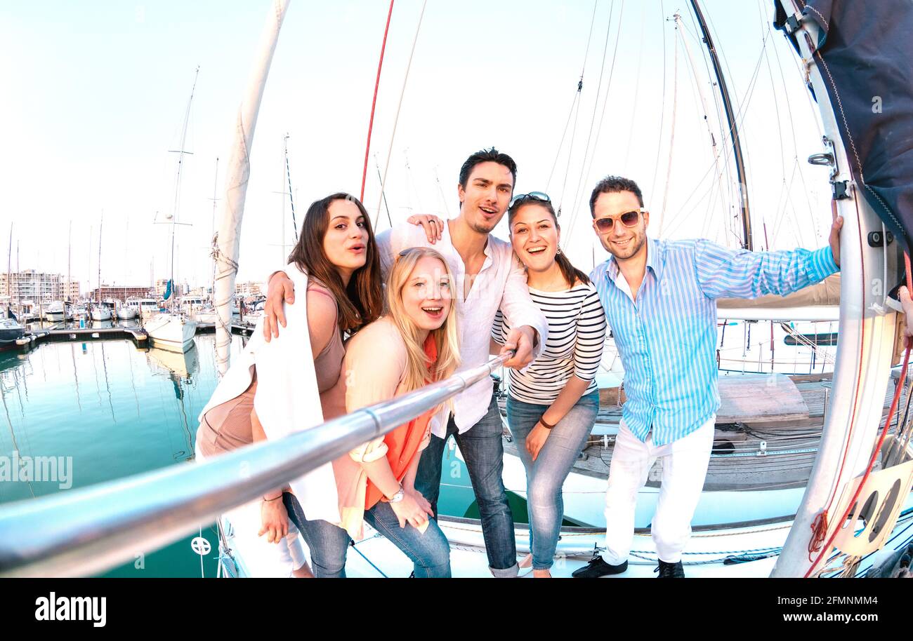 Gruppo di amici che prende foto selfie con bastone su vela di lusso Festa in barca - concetto di amicizia con giovani milleniali divertirsi insieme Foto Stock
